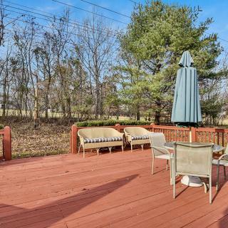 A spacious outdoor deck with patio furniture and an umbrella, surrounded by trees.