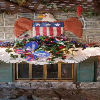 A patriotic-themed decoration above a fireplace featuring an eagle with an American flag motif and a colorful floral arrangement.