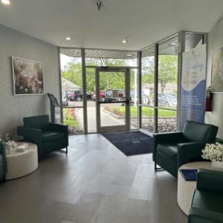 A modern lobby with comfortable seating and a view of the outside through glass doors.