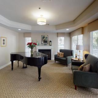 A cozy living room with a grand piano, elegant furniture, and a fireplace.