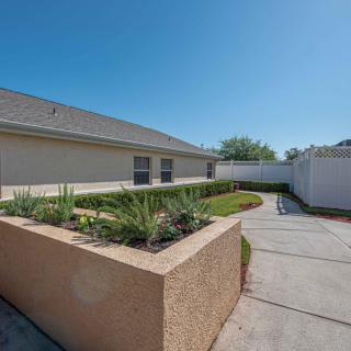 A sunny backyard with a landscaped garden and a spacious driveway.