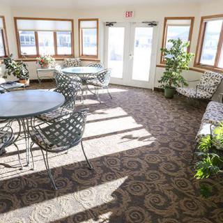 A bright sunroom with tables, chairs, and indoor plants.