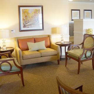 A cozy living room with a sofa, chairs, lamps, and wall art.