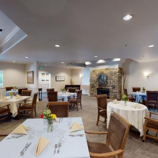 A cozy dining room with neatly arranged tables and chairs, featuring warm lighting and decor.