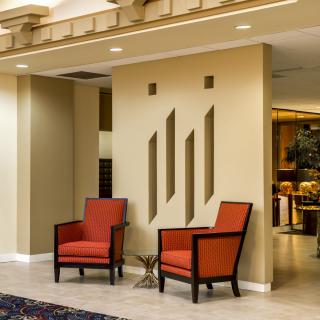 A modern interior with two red chairs in a well-lit lobby area.