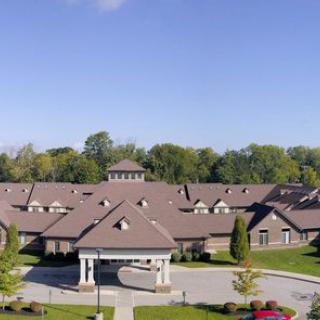 A large building complex surrounded by trees with a clear blue sky above.