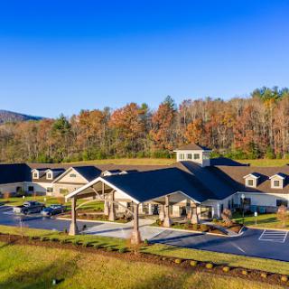 A picturesque view of a modern facility nestled in a serene landscape, surrounded by autumn foliage and mountains.