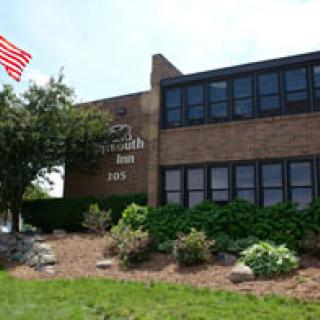 A brick bank building with an American flag and landscaped surroundings.