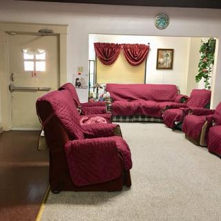 A cozy living room with red upholstered furniture and elegant curtains.