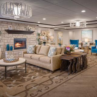 A beautifully decorated living room featuring a cozy sofa, elegant chandeliers, and a warm fireplace.