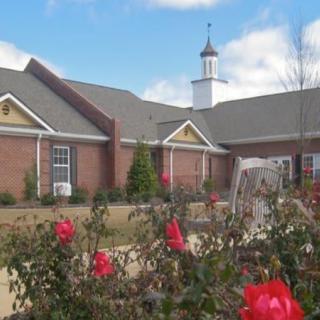A charming church building with a garden of vibrant red flowers in the foreground.