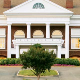 A symmetrical colonial-style building with prominent columns and landscaped surroundings.