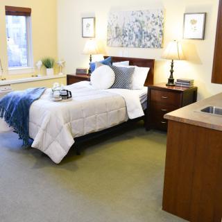 A cozy bedroom with a neatly made bed, bedside tables, lamps, and wall art.