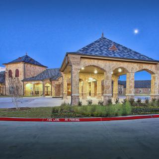 A beautifully lit building with arched entrances and a tiled roof under an evening sky.