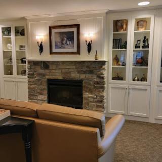 A cozy living room featuring a stone fireplace and elegant shelving.