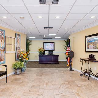 A well-decorated office reception area with a central desk, artwork on the walls, and potted plants.
