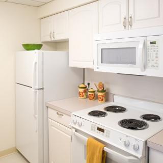 A modern kitchen with white cabinets, featuring a refrigerator, stove, and microwave.