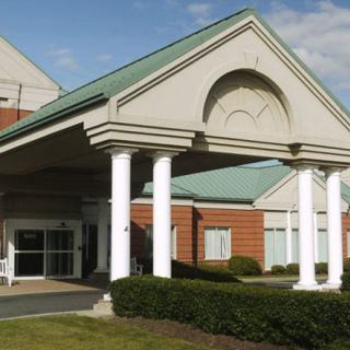 An exterior view of a building entrance with columns and a green roof.