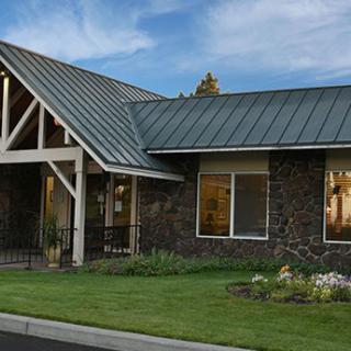 A modern building with a metal roof and landscaped lawn.
