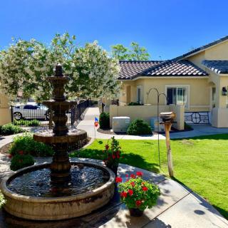 A sunny garden with a fountain in front of a house.