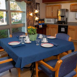 A cozy dining area featuring a well-set table with a blue tablecloth and decorative flowers.