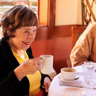 A woman enjoying a cup of coffee at a restaurant.