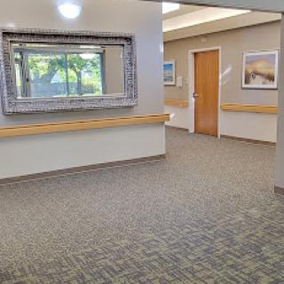 A well-lit hospital hallway featuring a decorative mirror and artwork on the walls.