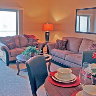 A cozy living room and dining area featuring comfortable sofas, a stylish lamp, and an inviting table setting.
