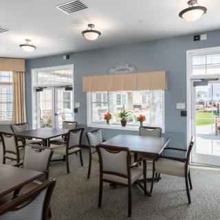 A bright and airy community dining area with neatly arranged tables and chairs.