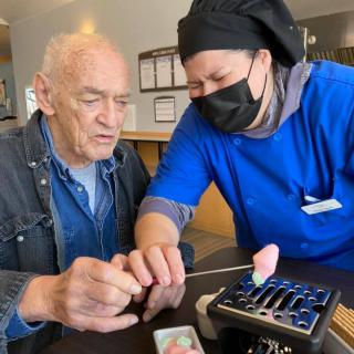 An elderly man and a chef work together on a culinary project.