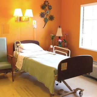 A well-lit hospital room with a single bed, chair, and decorative elements.