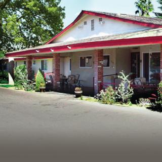 A charming motel with a welcoming exterior, surrounded by lush greenery.