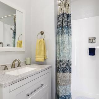 A modern bathroom with a shower, vanity with mirror, and decorative towels.