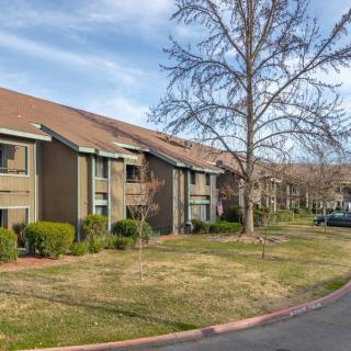 A suburban apartment complex with a well-maintained lawn and trees.