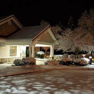 A cozy house illuminated at night, surrounded by freshly fallen snow.