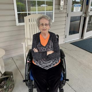 An elderly woman sitting comfortably in a wheelchair, enjoying the outdoors.