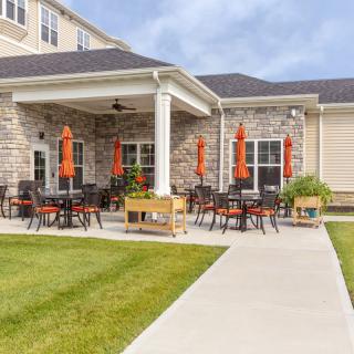 A patio area with tables, chairs, and umbrellas outside a building.