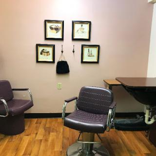 A cozy corner of a hair salon featuring stylish chairs and framed artwork on the wall.