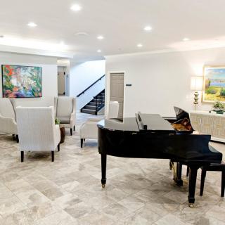 A modern living room featuring a grand piano, elegant furniture, and vibrant artwork.