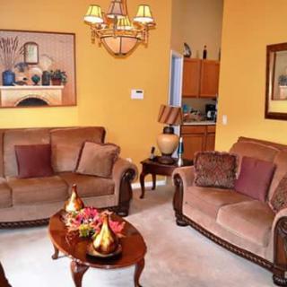 A cozy living room with brown sofas, a wooden coffee table, and yellow walls adorned with artwork.