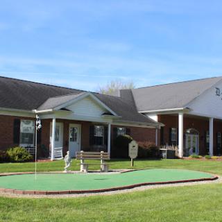 A well-maintained residential building featuring a small golf putting green and a beautiful lawn under a clear blue sky.