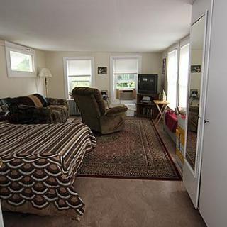 A cozy living room featuring a sofa, armchair, TV, and carpet.