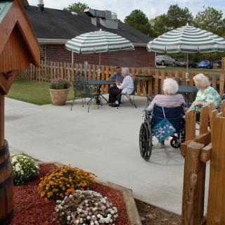 Elderly individuals enjoying a peaceful afternoon in a garden setting at a care facility.