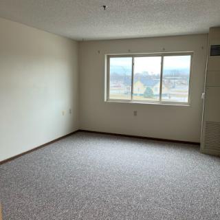A spacious empty room with a window allowing natural light.