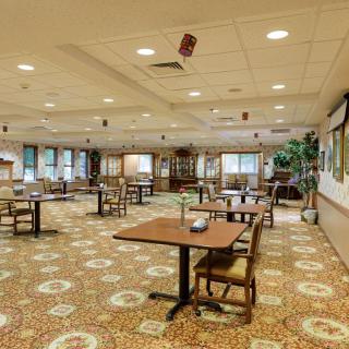 Spacious dining area with multiple tables and chairs arranged on a patterned carpet.