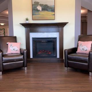 A cozy living room featuring a fireplace flanked by two leather armchairs with floral cushions.