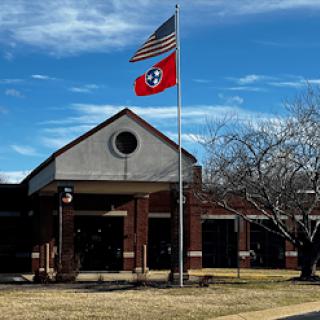 A view of a building showcasing the American and Tennessee flags against a clear blue sky.