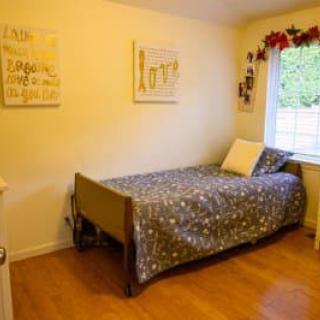 A cozy bedroom with a single bed, decorated with wall art and featuring a wooden floor.