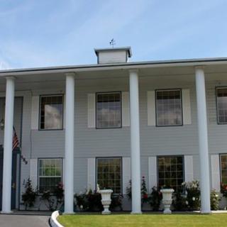 A two-story building with large columns and multiple windows against a blue sky.