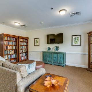 A cozy living room featuring bookshelves, a sofa, a television on the wall, and a coffee table with decorative items.